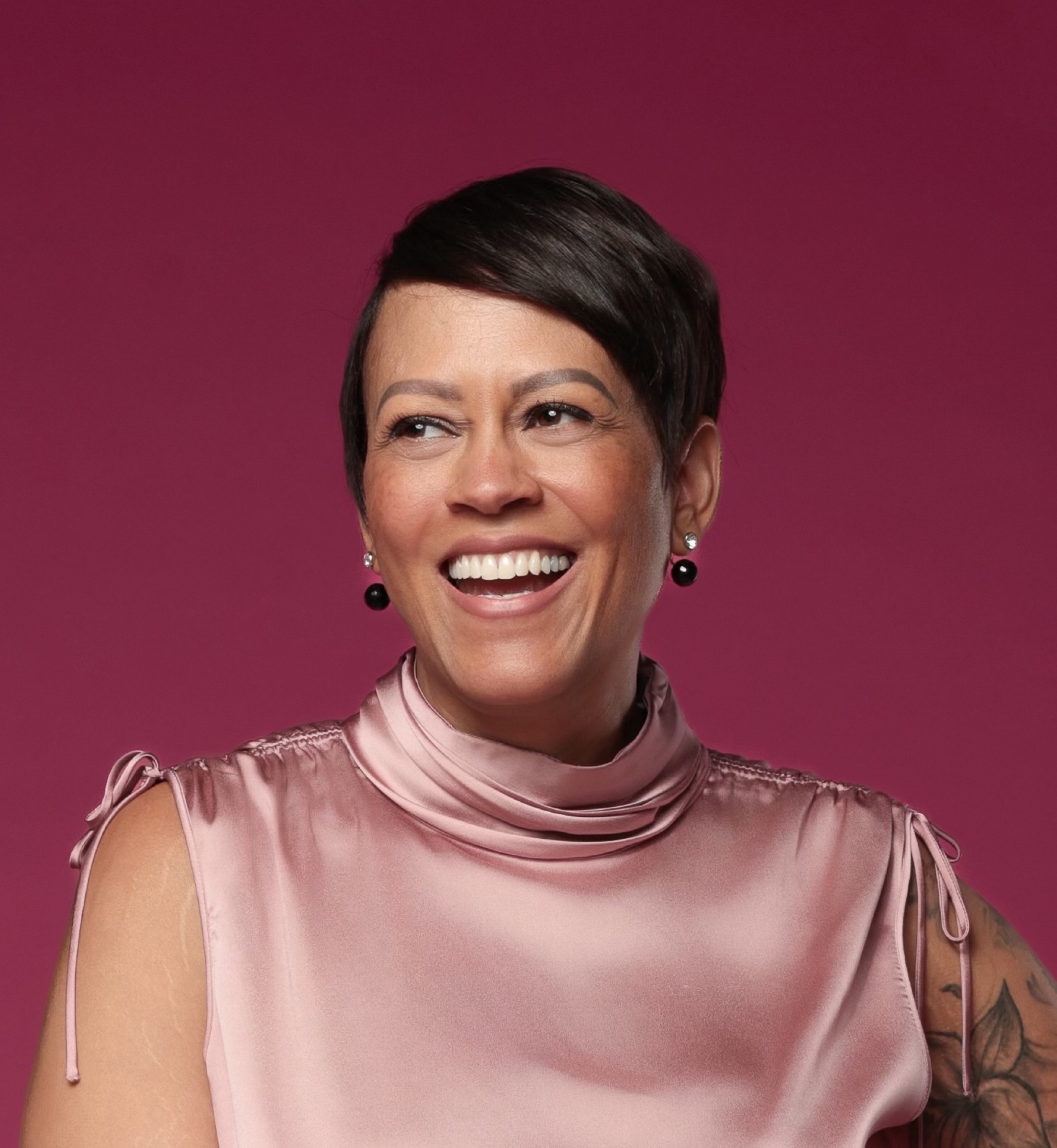 Lorrena Black smiling in a rose satin top against a wine backdrop